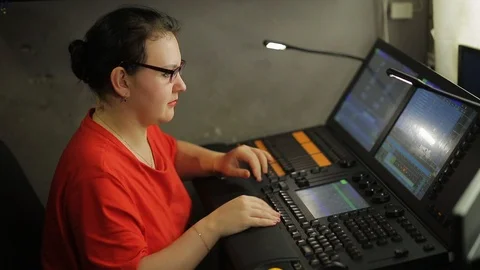 A female illuminator at the remote control programs the stage light for the show Stock Footage 125203073
