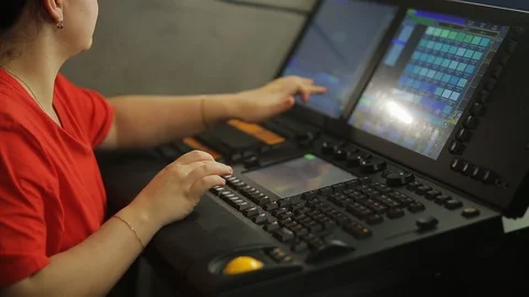A female illuminator at the remote control programs the stage light for the show Stock Footage 128393049