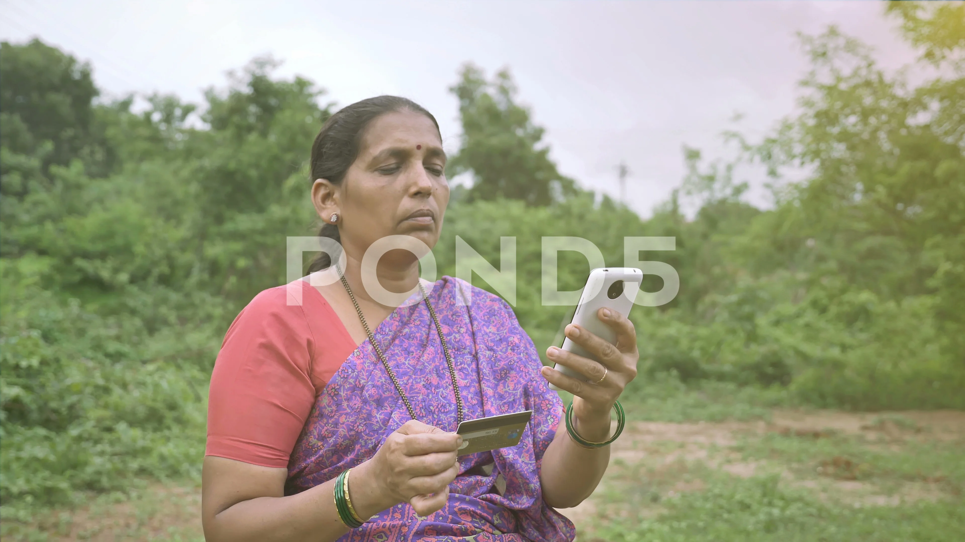 A female Indian farmer holding a mobile phone and credit or debit card,  India