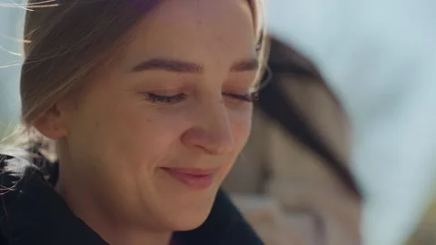 Female individuals engaged in reading notes while smiling outside in sunlight 스톡 동영상 329464964