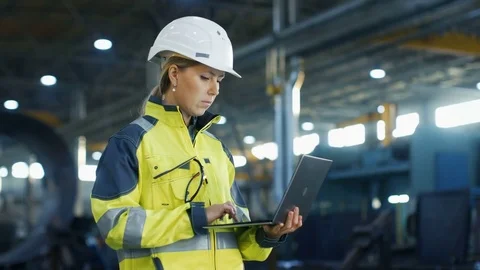 Female Industrial Engineer in the Hard Hat Uses Laptop Computer while Standing  Stock Footage