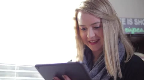 Female Inside Smiling As She Clicks And Swipes Her Fingers On a Tablet Stock Footage 62822602