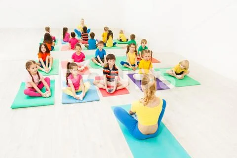 Female instructor giving yoga class for kids Stock Photos