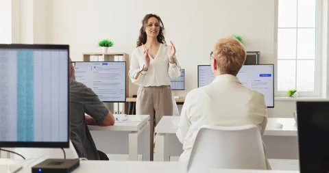 Female instructor teaching adults in computer classroom during corporate Stock Footage 339865800