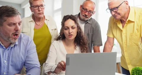 Female instructor teaching technology to senior students around laptop in Stock Footage 340776258