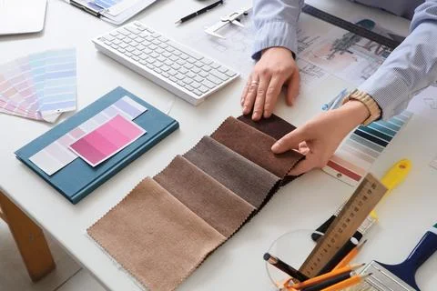 Female interior designer with fabric samples working at table in office Stock Photos