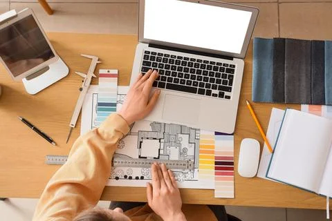 Female interior designer working with blank laptop on table in studio, top vi Stock Photos