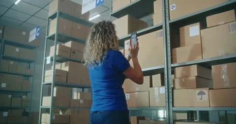 Female inventory manager scans code on cardboard box, checks parcel information Stock Footage 307577074