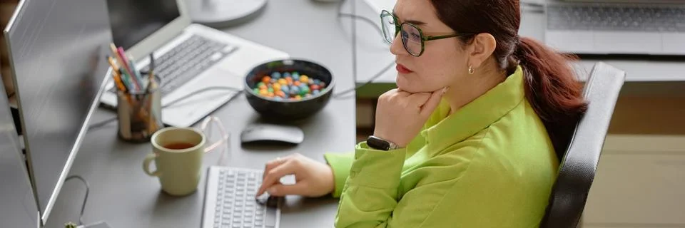 Female IT Developer Thinking while Typing on Computer Keyboard in Office Stock Photos