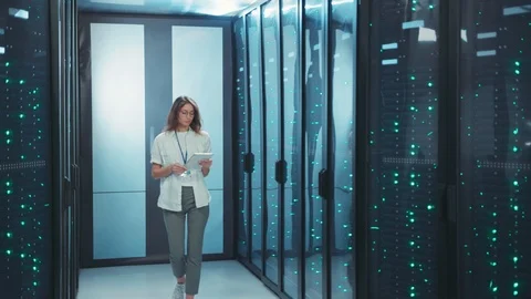 Female IT engineer performing data center backups with digital laptop. Cheerful Stock Footage 119782968