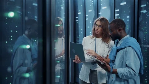 Female IT professional instructing young server technician inside working server Stock Footage 121159099