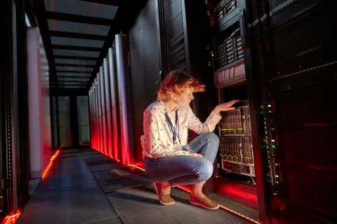 Female IT technician examining panel in dark server room Foto stock