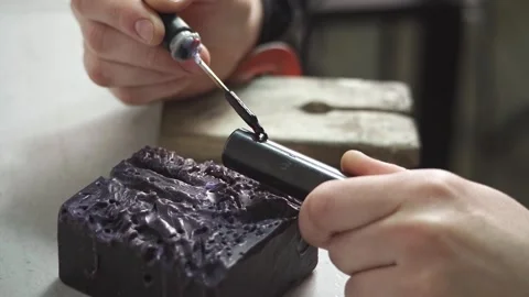 A female jeweler constructs a unique ring design using wax melting Stock Footage 277883862