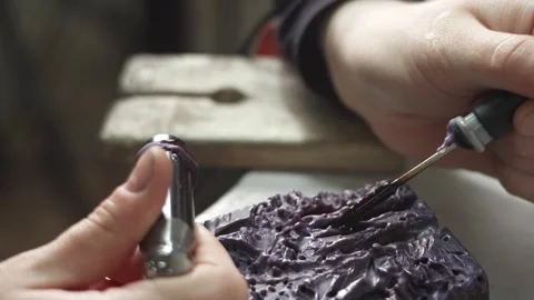 A female jeweler constructs a unique ring design using wax melting Stock Footage 277883964