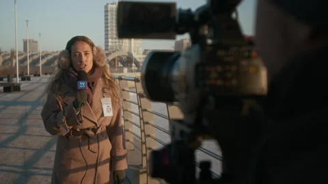 Female Journalist Delivering News Report on River Bridge for Local Channel Stock Footage 300404519