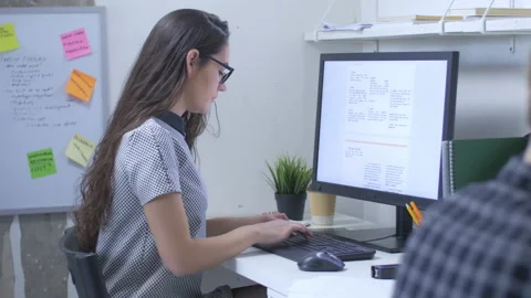 Female journalist in front of large computer monitor, writing news report Stock Footage 142239863