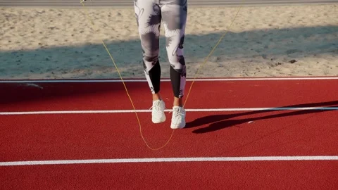 Female jumping rope in the rays of the sun. Woman legs jumping rope skipping Stock Footage 161069841