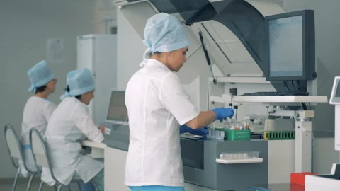 Female lab expert is putting samples into clinical chemistry analyzer Video stock 92664103