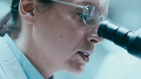 Female Lab Scientist Using Microscope and Talking in Research Center Stock Footage 331337785