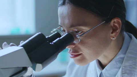 Female Lab Technician Performing Scientific Research with Microscope Stock Footage 337320485
