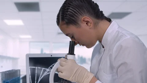A female lab technician sitting at a table next to a laptop in a modern medical Stock Footage 108329148