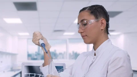 A female lab technician sitting at a table next to a laptop in a modern medical Stock Footage 108330689