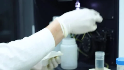 A female lab technician takes a sample from a test tube in the lab Stock Footage 249601255