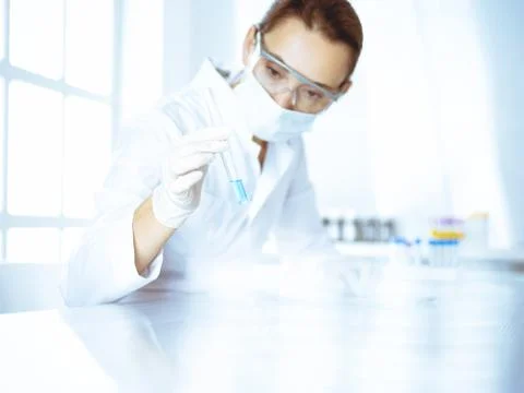 Female laboratory assistant analyzing test tube with blue liquid. Medicine Foto stock