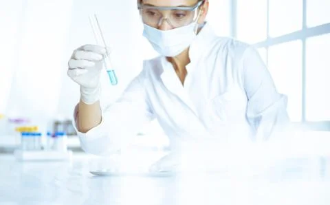 Female laboratory assistant analyzing test tube with blue liquid. Medicine Stock Photos