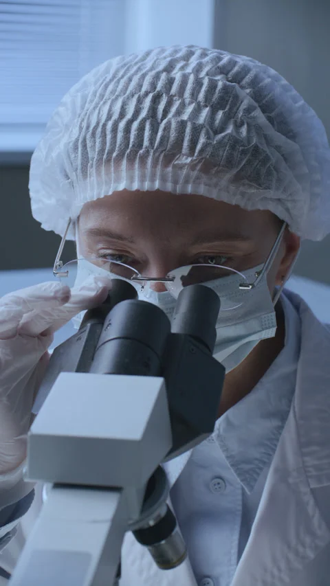 Female Laboratory Technician Looking into Binocular Microscope Stock Footage 337321366