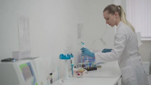 Female laboratory technician using a pipette while working with samples in a Stock Footage 323762087