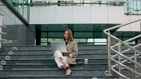 Female lawyer while working on a modern computer sitting on the stairs in front Stock Footage 232984064