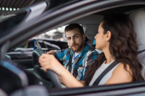Female learner driver student sitting in the car. Male instructor holding paper Stock Photos