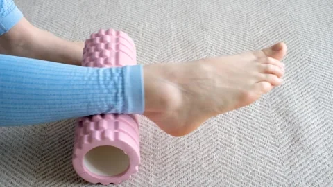 Female leg doing exercise with pink foam roller on carpet. Stock Footage 240363969