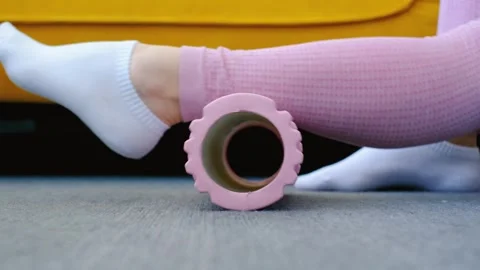 Female leg doing exercise with pink foam roller on carpet against the background Stock Footage 302943528