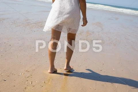 Female leg walking on the beach in the ocean. Stock Photos