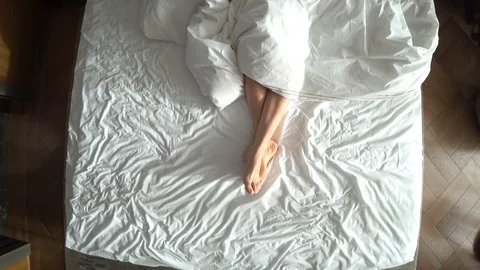 Female legs in bed view from above, white bedding Stock Footage 87975449