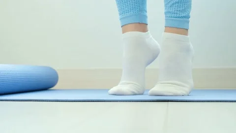 Female legs doing exercises lifting on toes close-up on blue background, front Stock Footage 234581255