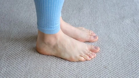 Female legs doing exercises lifting on toes close-up on light background. Vidéo 240600852