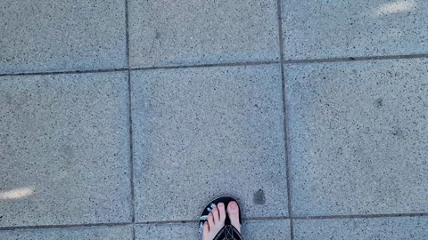 Female legs in flip flops walking down the street, first person view Stock Footage 295889183