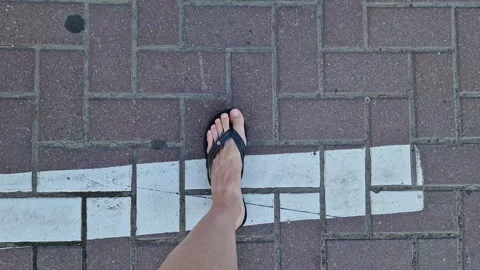 Female legs in flip flops walking down the street, first person view Stock Footage 295889188