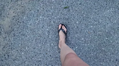 Female legs in flip flops walking down the street, first person view Stock Footage 295889192