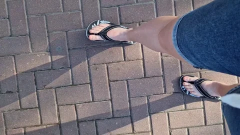 Female legs in flip flops walking down the street, first person view Stock Footage 295889345