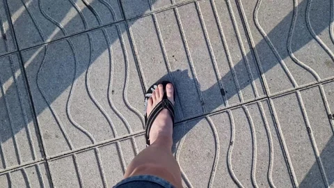 Female legs in flip flops walking down the street, first person view Stock Footage 295889649