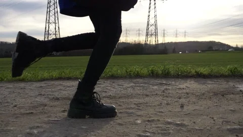 Female legs in solid black boots running on dirt road in sunset time Stock Footage 157007527