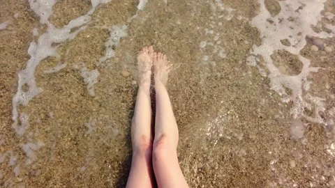 Female legs wading through shallow sea surf at the beach daytime Video stock 342127220