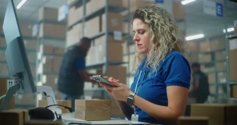 Female logistics manager scans small parcels using smartphone, works in Stock Footage 307577841