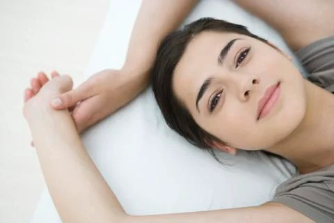 Female lying on pillow, arms raised, smiling at camera Stock Photos