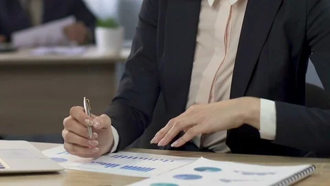 Female manager comparing two graphs and making notes at the office, business Stock Footage 79929782