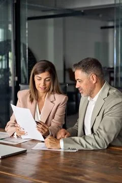 Female manager consulting client with documents at office meeting. Vertical. Stock Photos
